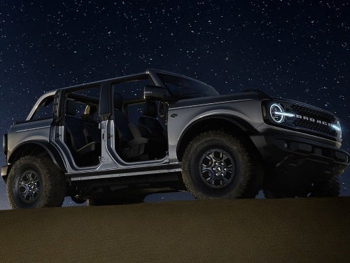 2024 Ford Bronco parked on a sand hill at night under the stars