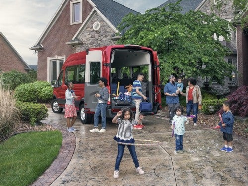 2024 Ford Transit parked in a driveway with a large family about to load into vehicle